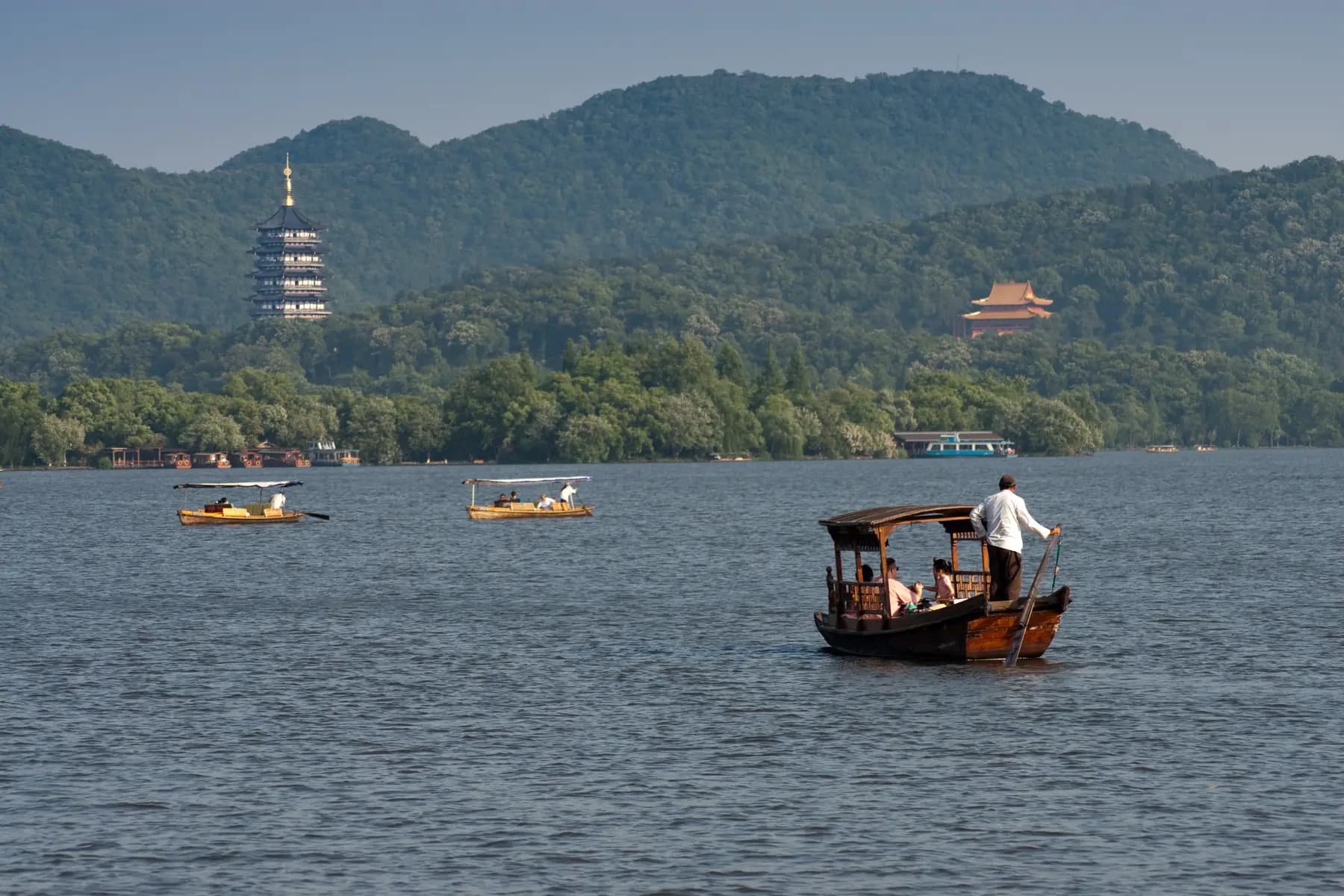 Small boats crossing West Lake with Leifeng Pagoda beyond the water