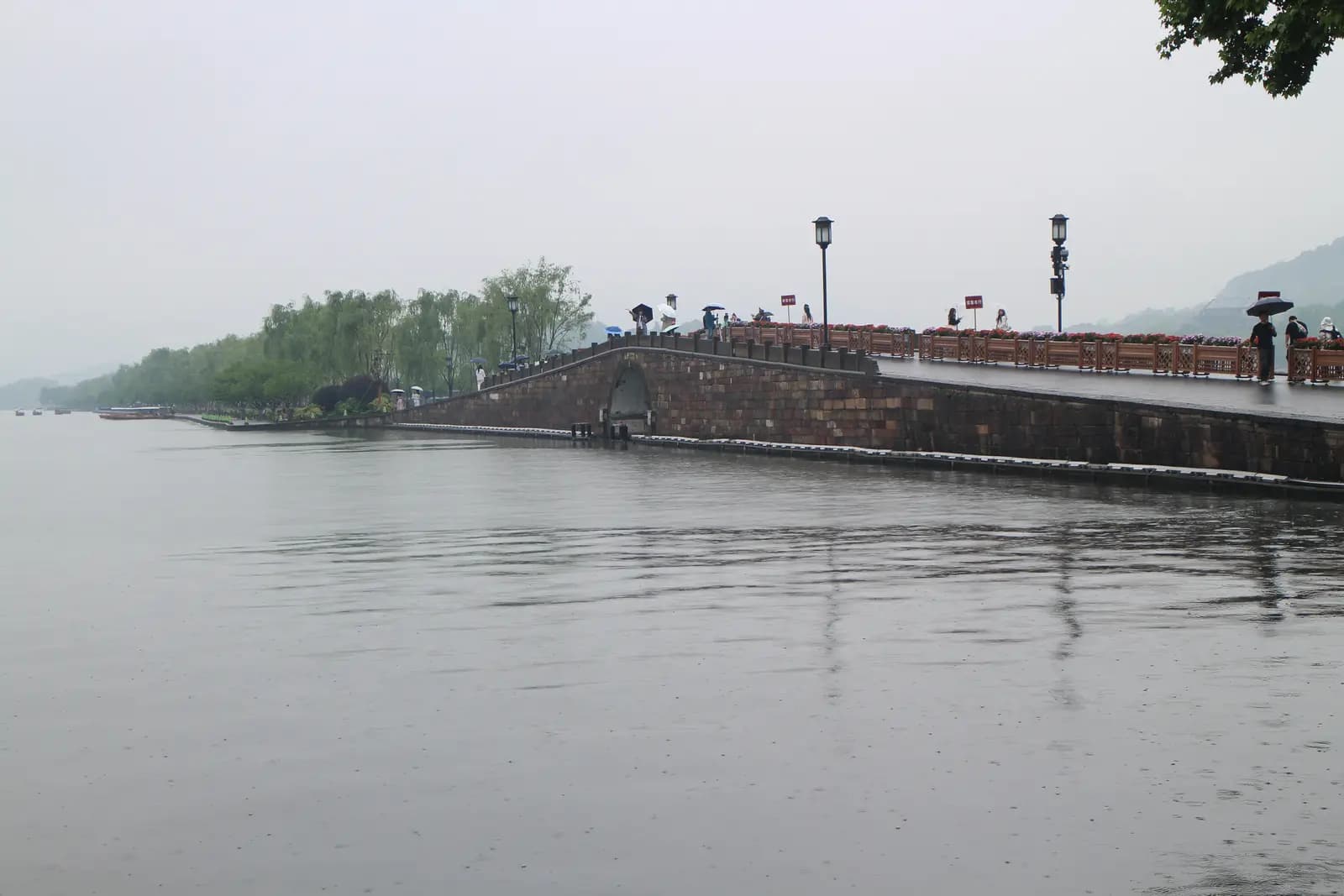 Visitors crossing Broken Bridge on a grey morning at West Lake